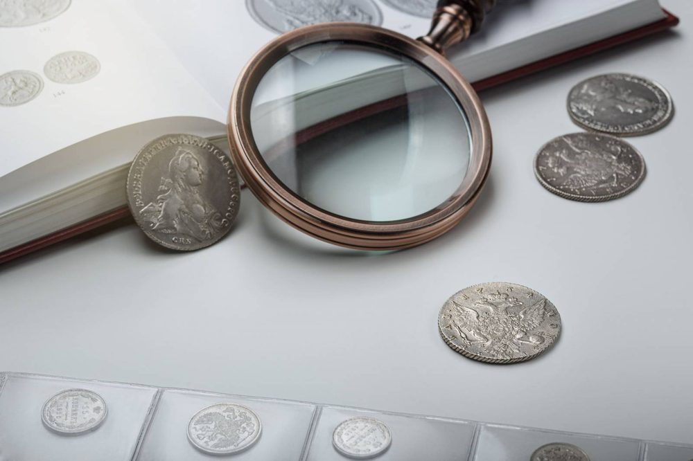 Loupe d’expert posée près de monnaies anciennes
